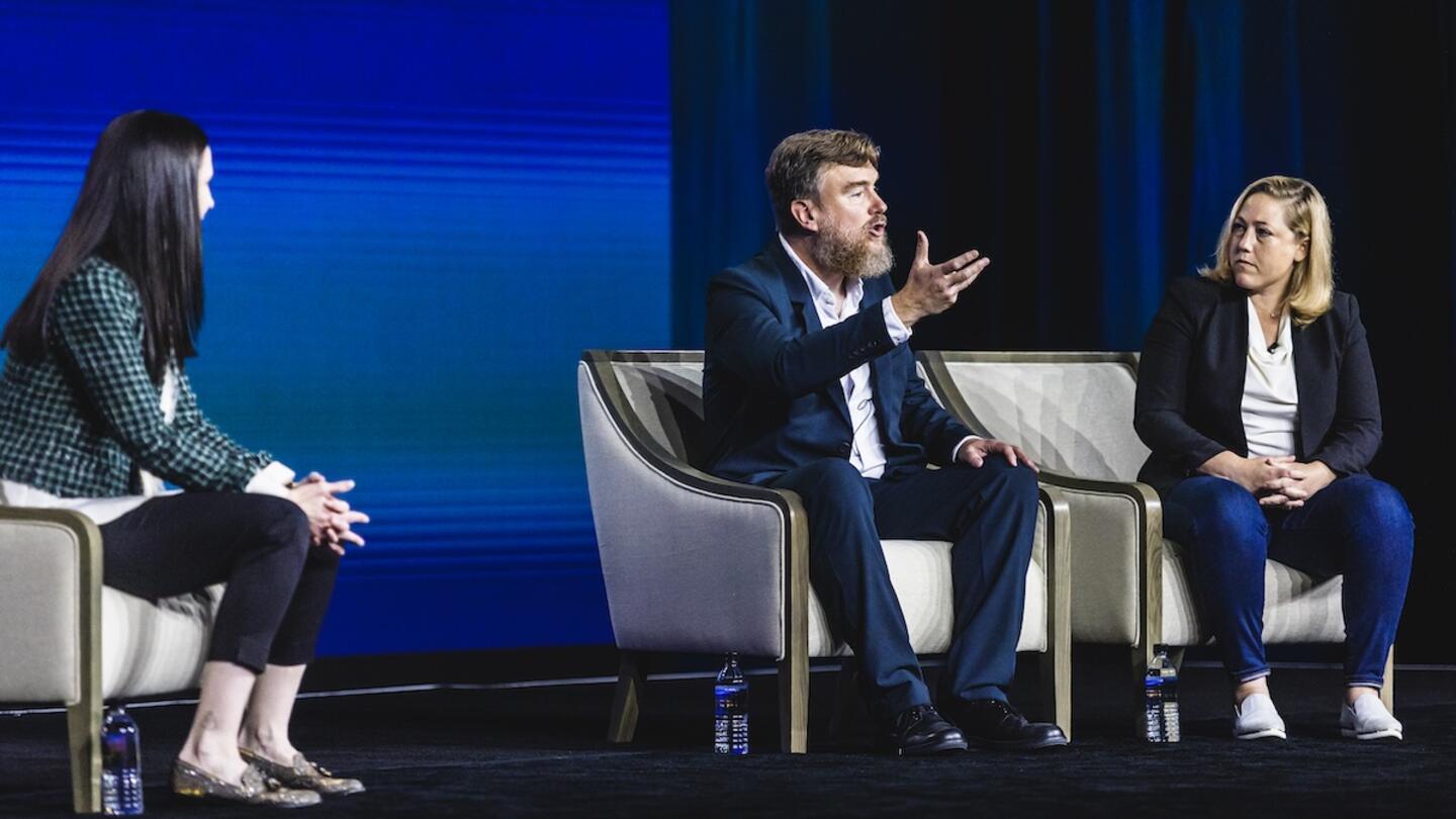 Three individuals on stage are conversing, showcasing the importance of protecting free speech.