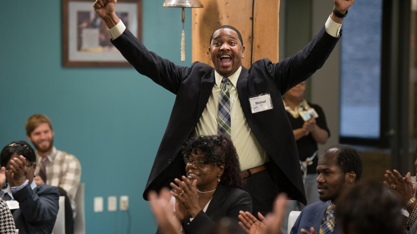 Entrepreneur with their hands raised up in celebration at an event.