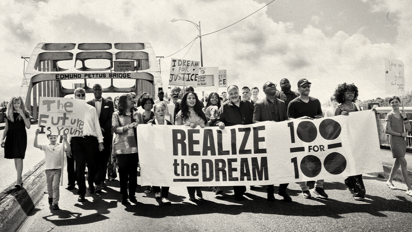 Group of people standing on a bridge holding a banner.