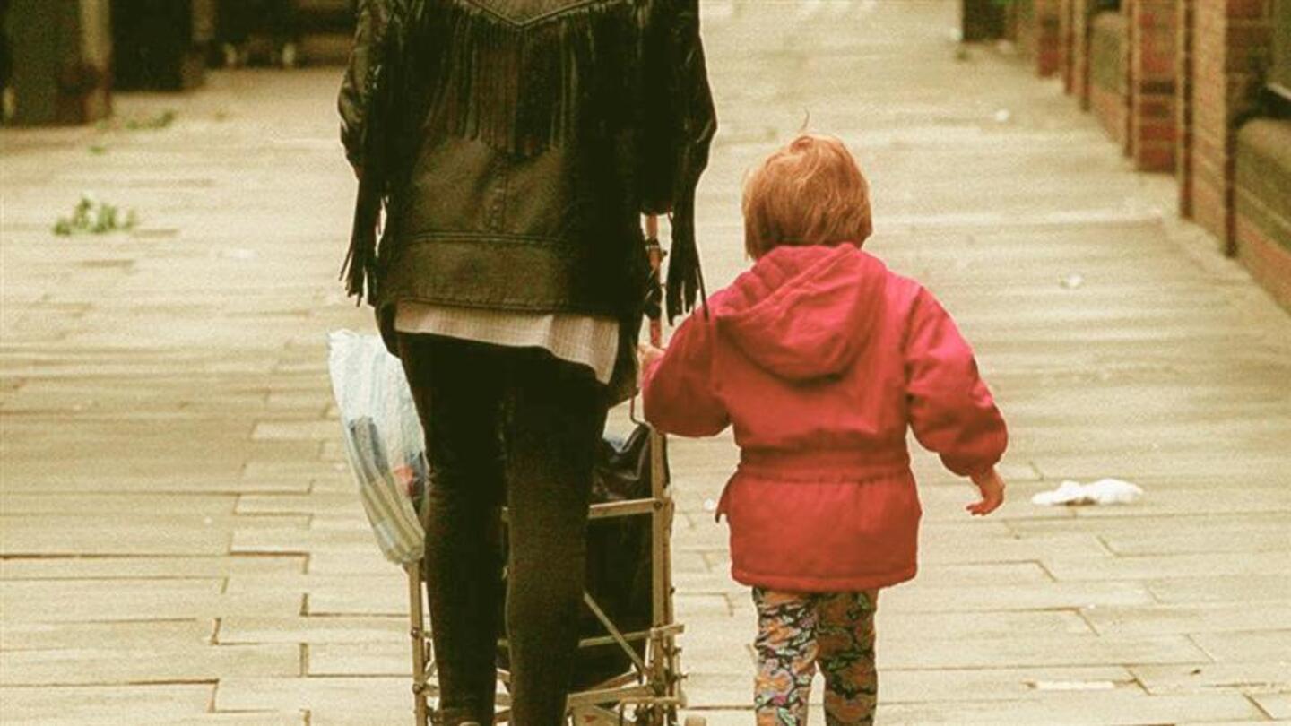 A mother and child walking with a stroller.