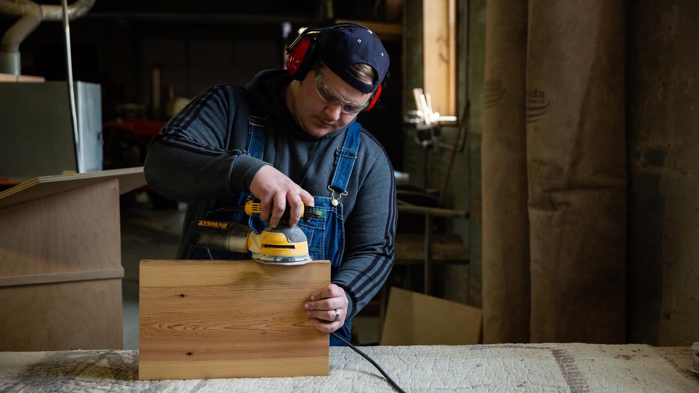 A young man using a power tool on a piece of wood