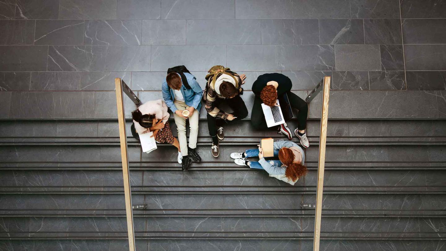 Students sit on stairs doing school work