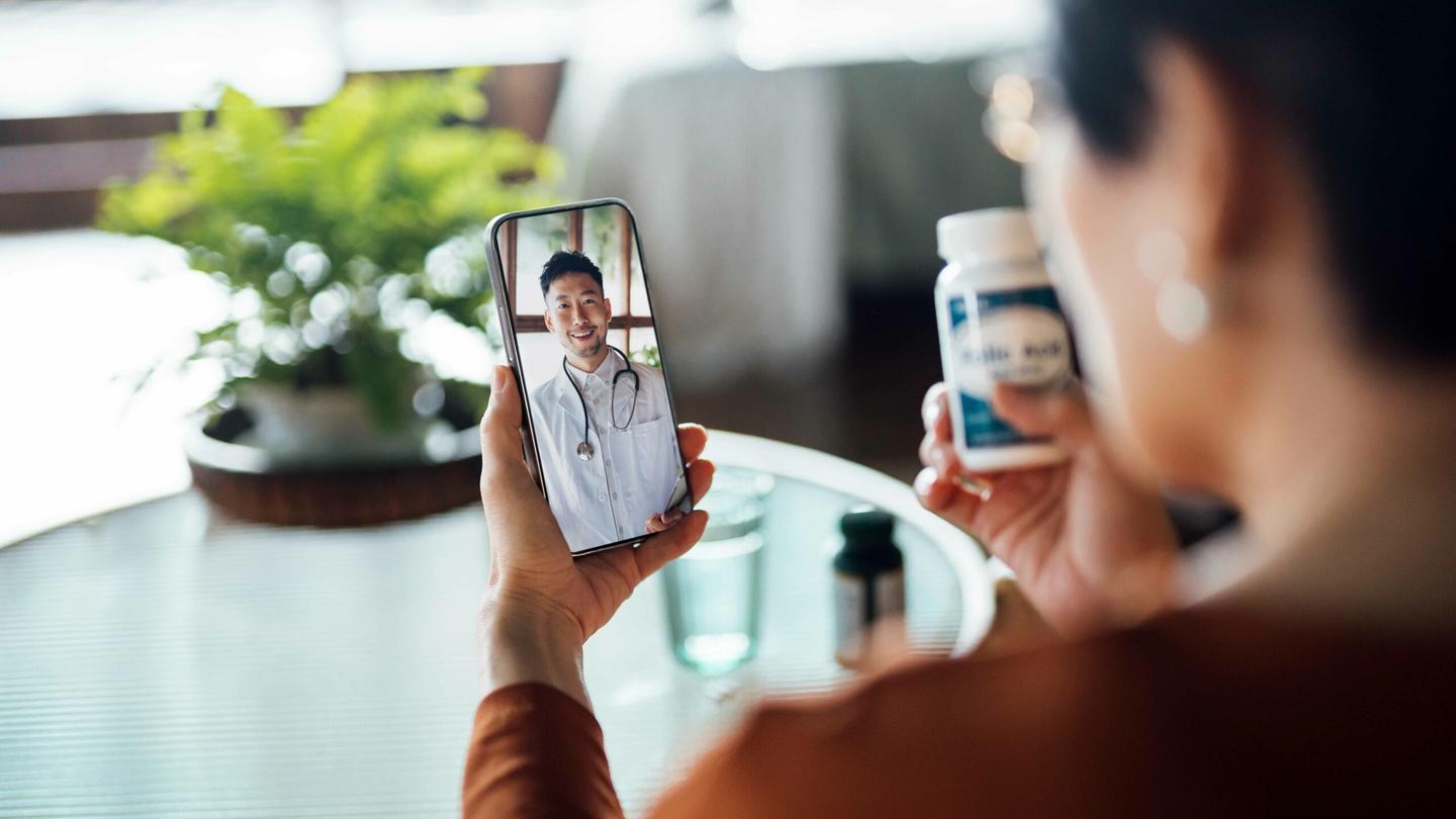 A woman talks to a doctor on her cell phone during a telehealth appointment