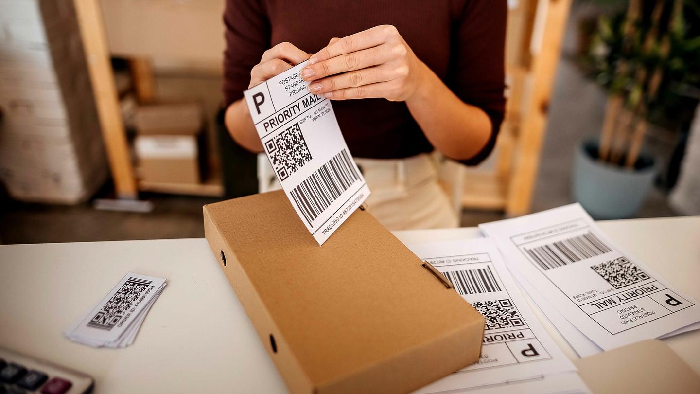 A woman placing a shipping label on a box