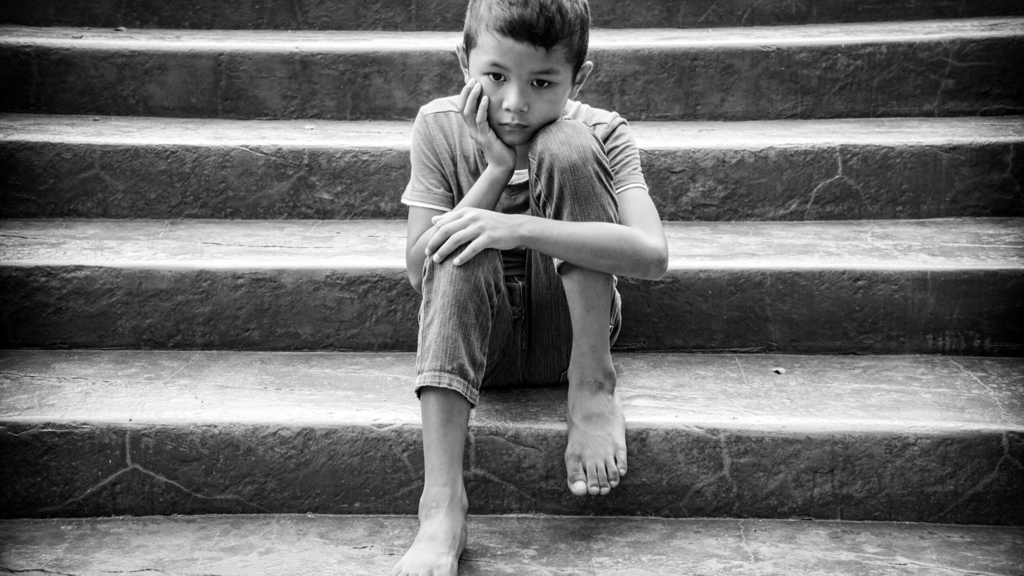 A child with no shoes sits on steps