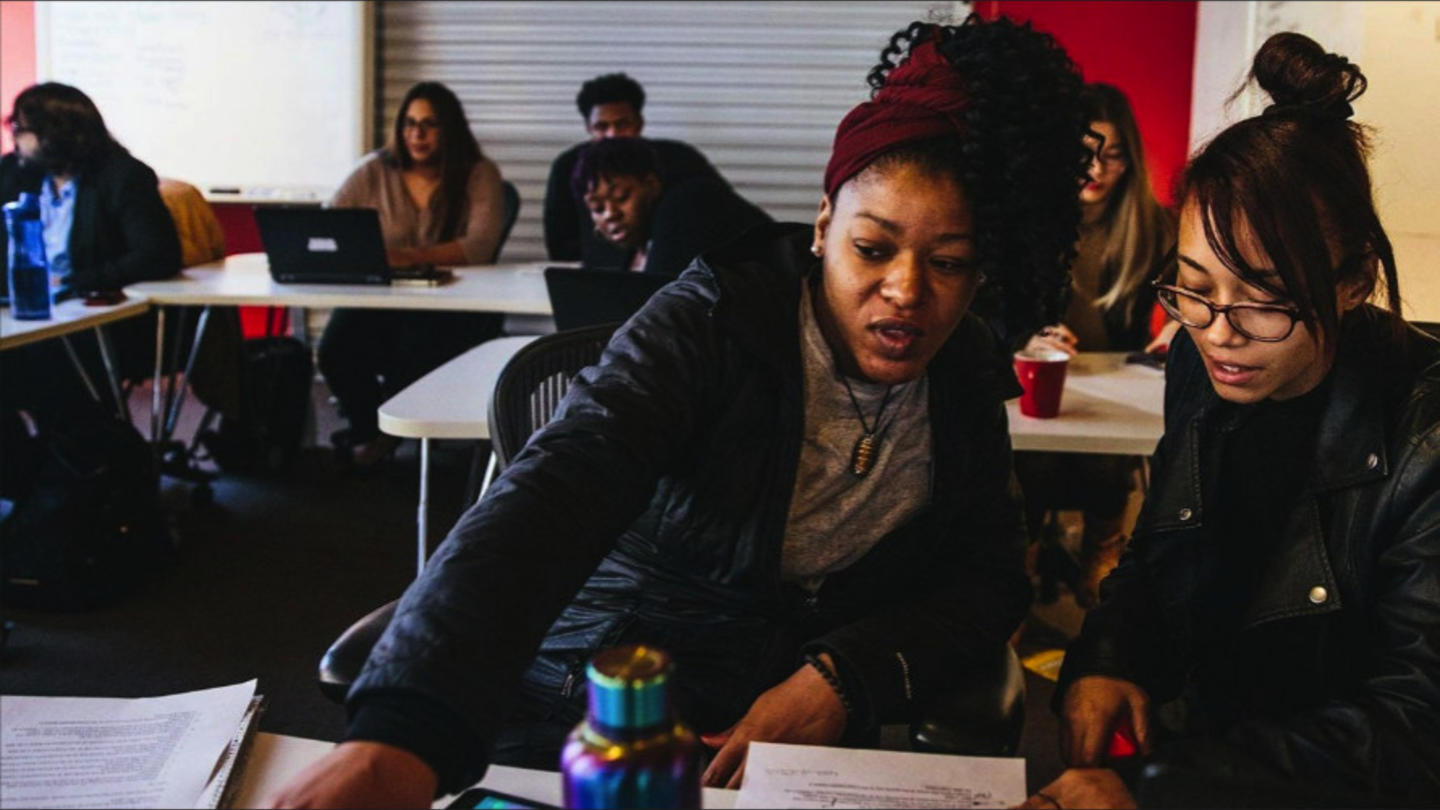 A woman helps another woman with school work