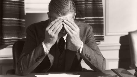 Man sitting at a desk with his face in his hands.
