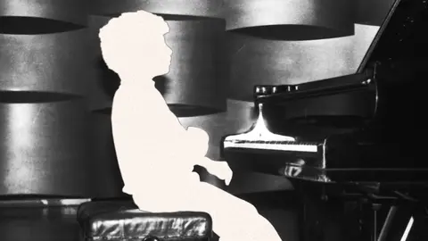 Outline of a person sitting in front of a piano.