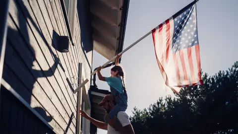 Putting up an American flag on a house.