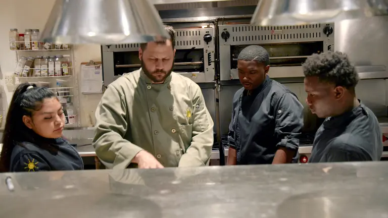 Cafe Momentum founder Chad Houser teachers interns how to cook.
