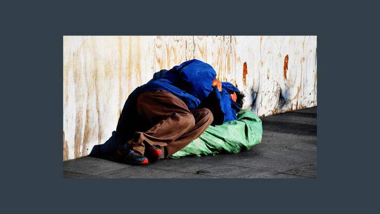 A person who is homeless sleeping on a sidewalk