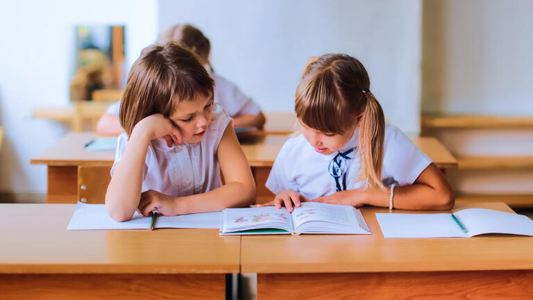 Two students reading together in a classroom