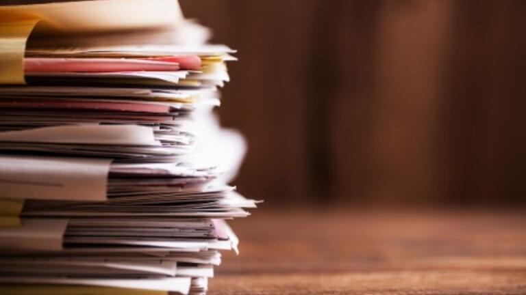 Stack of papers and folders on a wooden desk