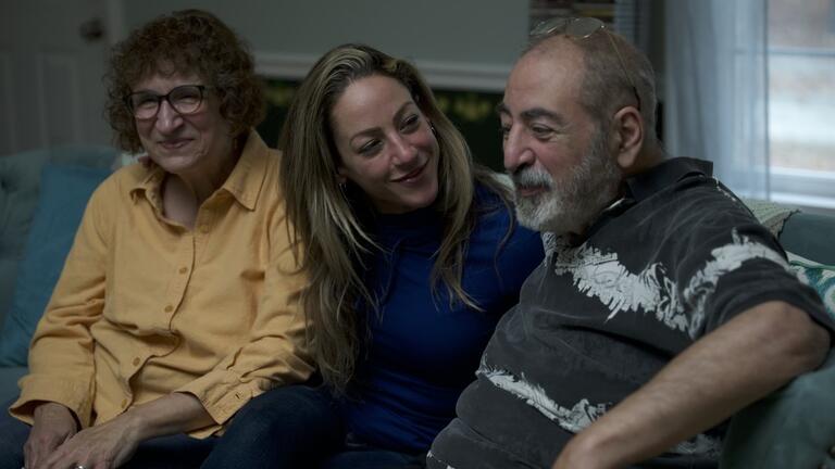 Three people sitting on a couch, smiling warmly and offering compassionate support to someone overcoming addiction.