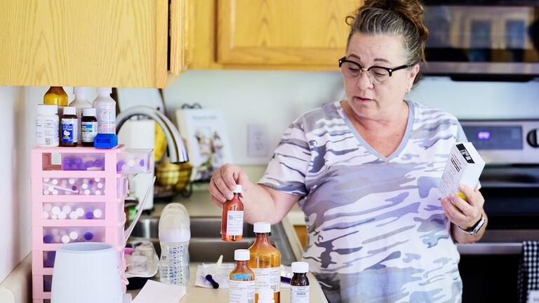 A caregiver organizes medications at home, highlighting patient-centered health care through personalized treatment management.