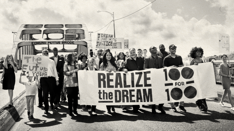 Group of people standing on a bridge holding a banner.