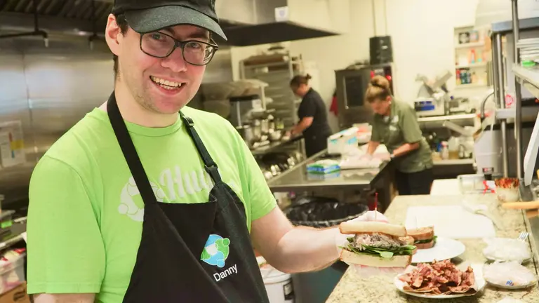 Hugs Cafe employee holding a sandwich.
