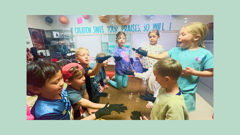 Children playing with bubbles in classroom.