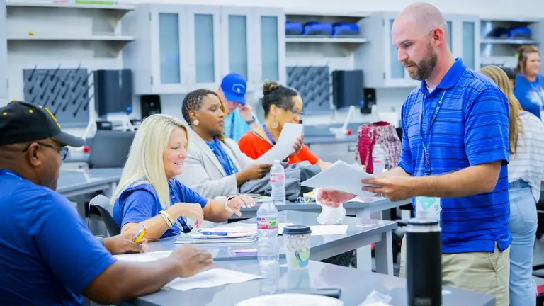 A group of adult learners and instructors in a classroom engage in hands-on learning at an Empowered event in Dallas.