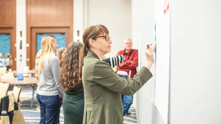 A worker writes ideas on a whiteboard during a workforce development strategy workshop.