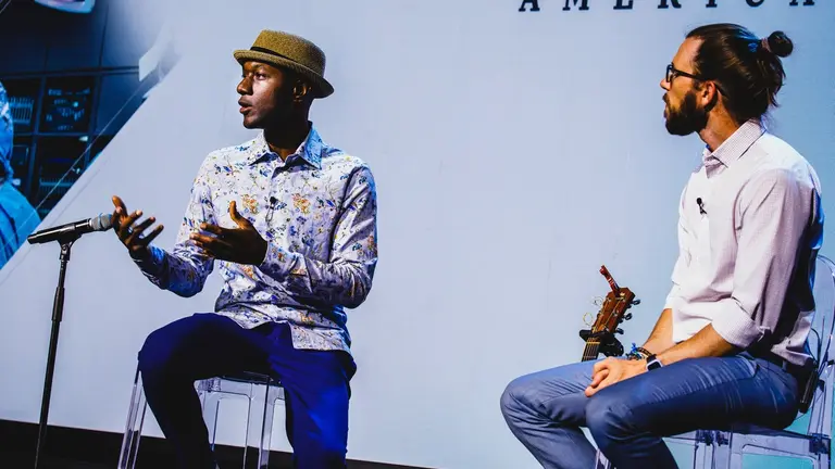 Two community leaders talk about solutions to the political divide on a stage with microphones.