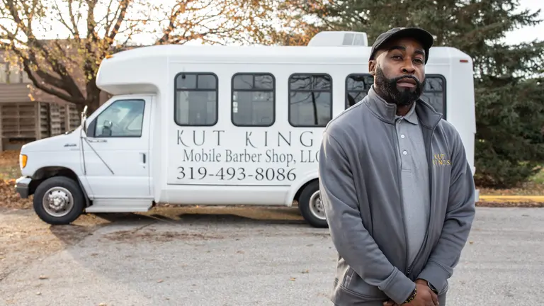 William Burt poses for a photo in front of his mobile barber shop
