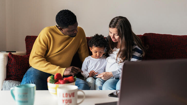 A man and woman sit with a child using a phone