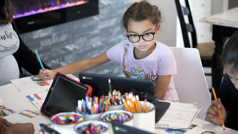 Student with glasses looking at a laptop to do school work