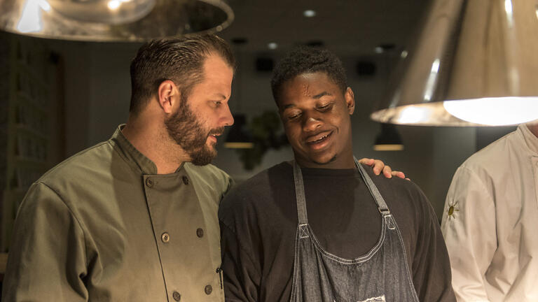 A man puts his hand over the shoulder of a Cafe Momentum intern working