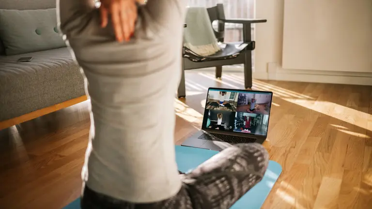 A woman stretches during a virtual yoga session