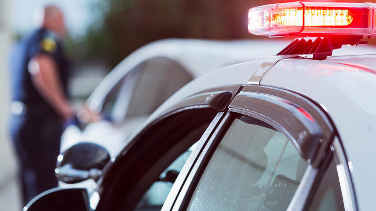 A police officer enters a squad car in the background