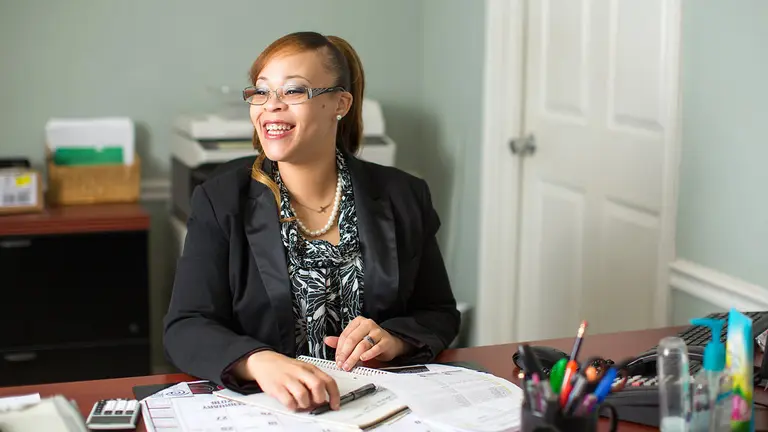 Odessa Moore smiling sitting behind a desk