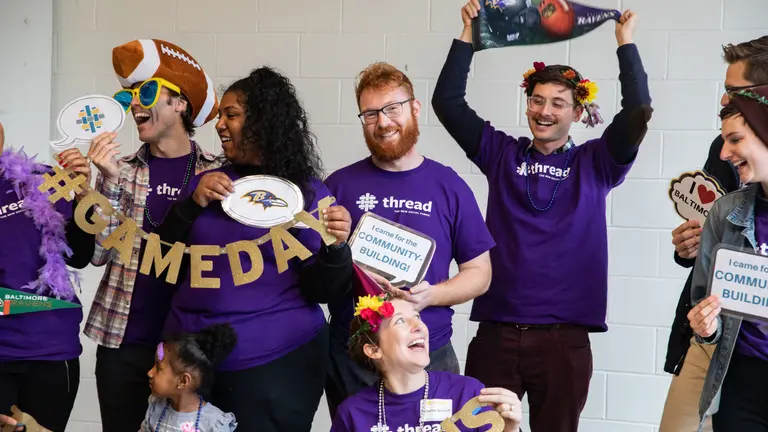 Thread volunteers pose for a photo holding ravens memorabilia