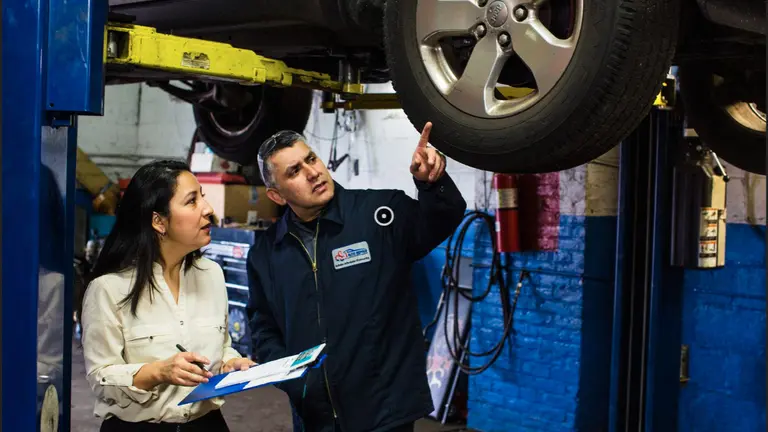Jose pointing at a tire in an auto shop