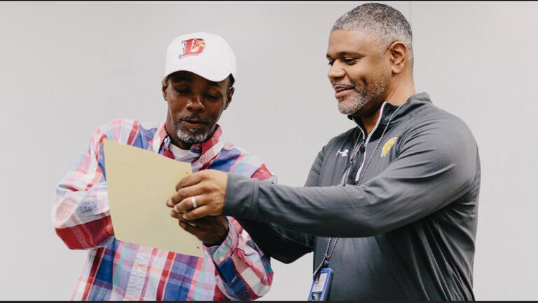 Richard Miles looks a document with another man