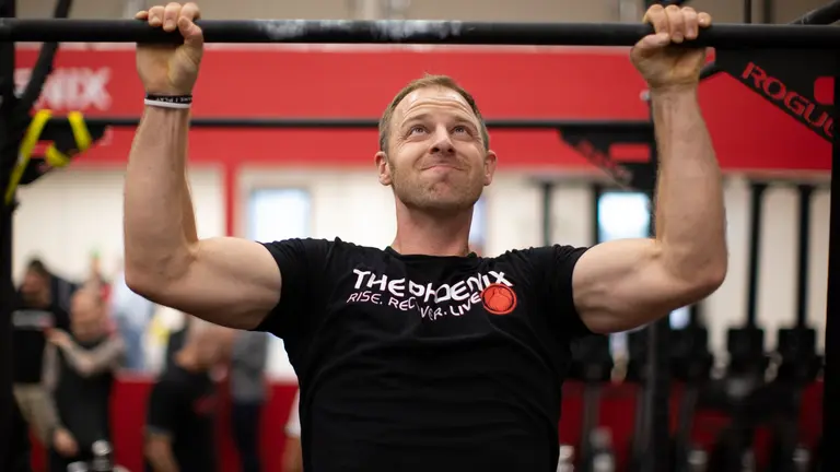 The Phoenix member does pull ups in a gym