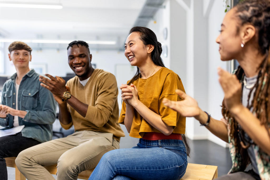 Four seated students clapping for each other.