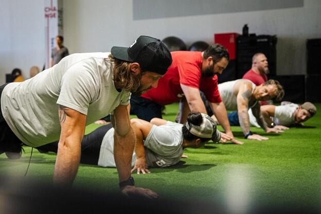 Founder David Vobora (left) doing pushups alongside ATF athletes. Jones third from right.
