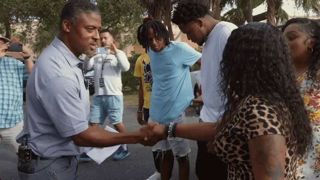 Warrick Dunn shaking hands with the recipient of a grant from Homes for the Holidays.