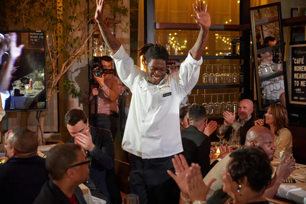 Lester raises his hands while diners cheer him on