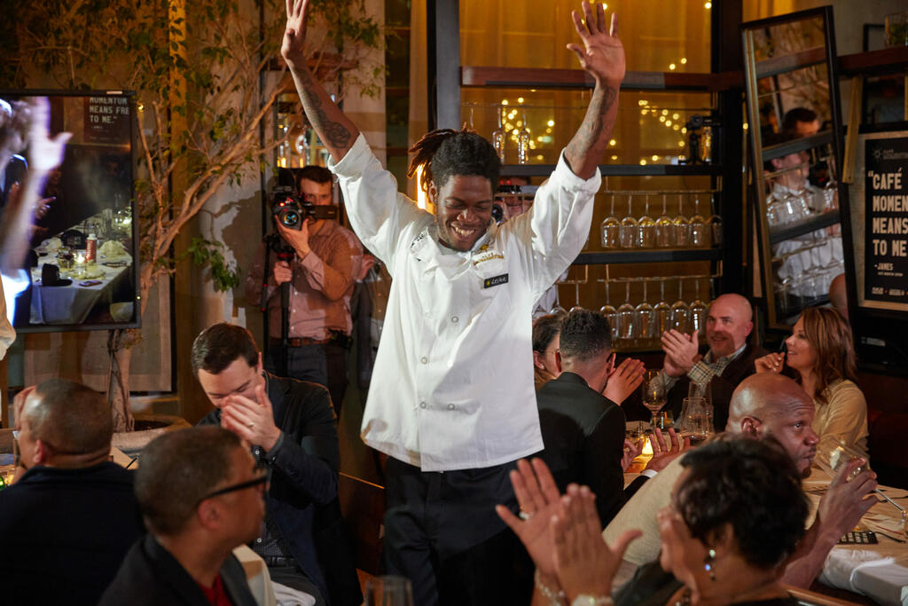Lester raises his hands while diners cheer him on