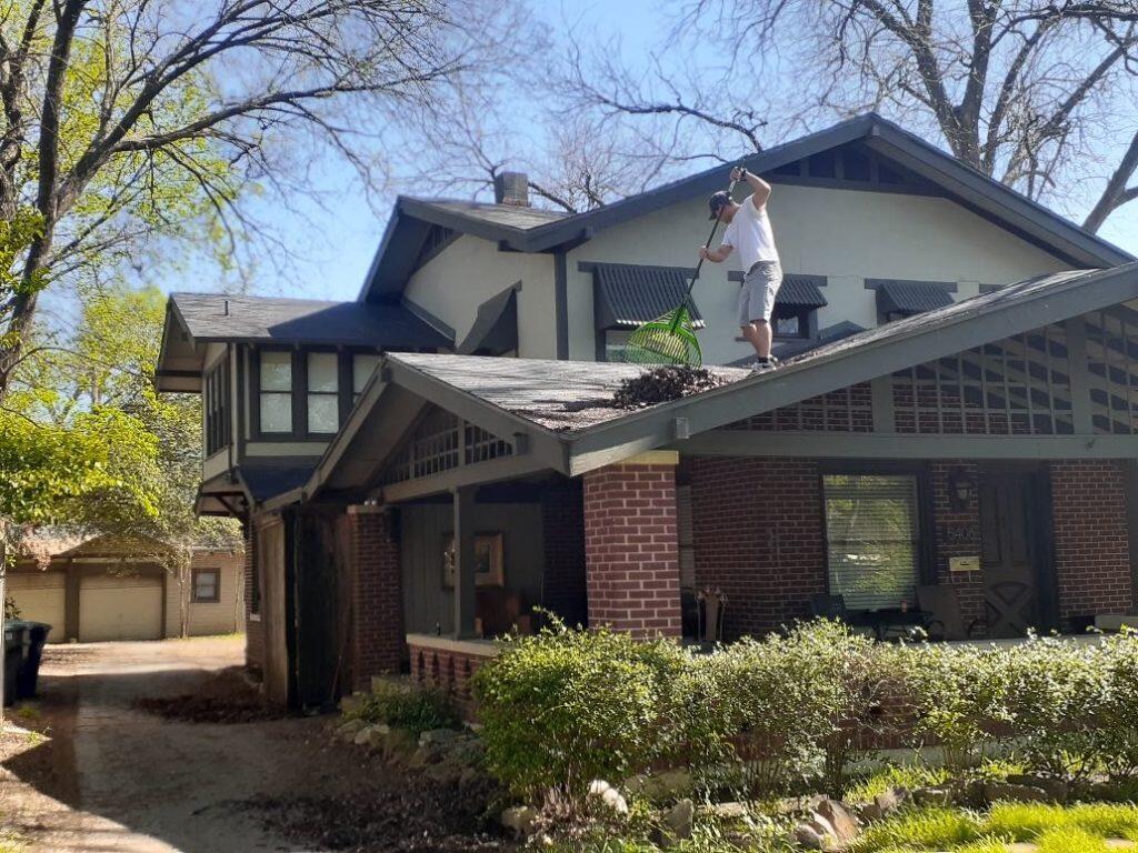 A man raking leaves off a roof