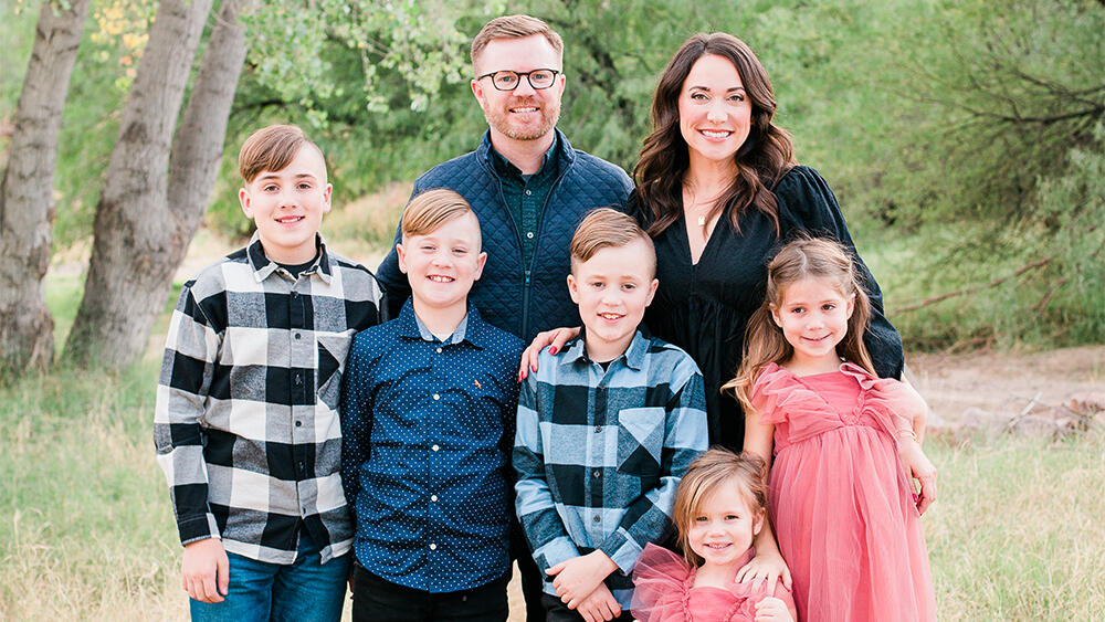 Jenny Clark poses outdoors with spouse and their children
