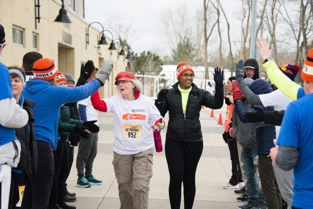 Two women walking between two columns of people sharing high fives