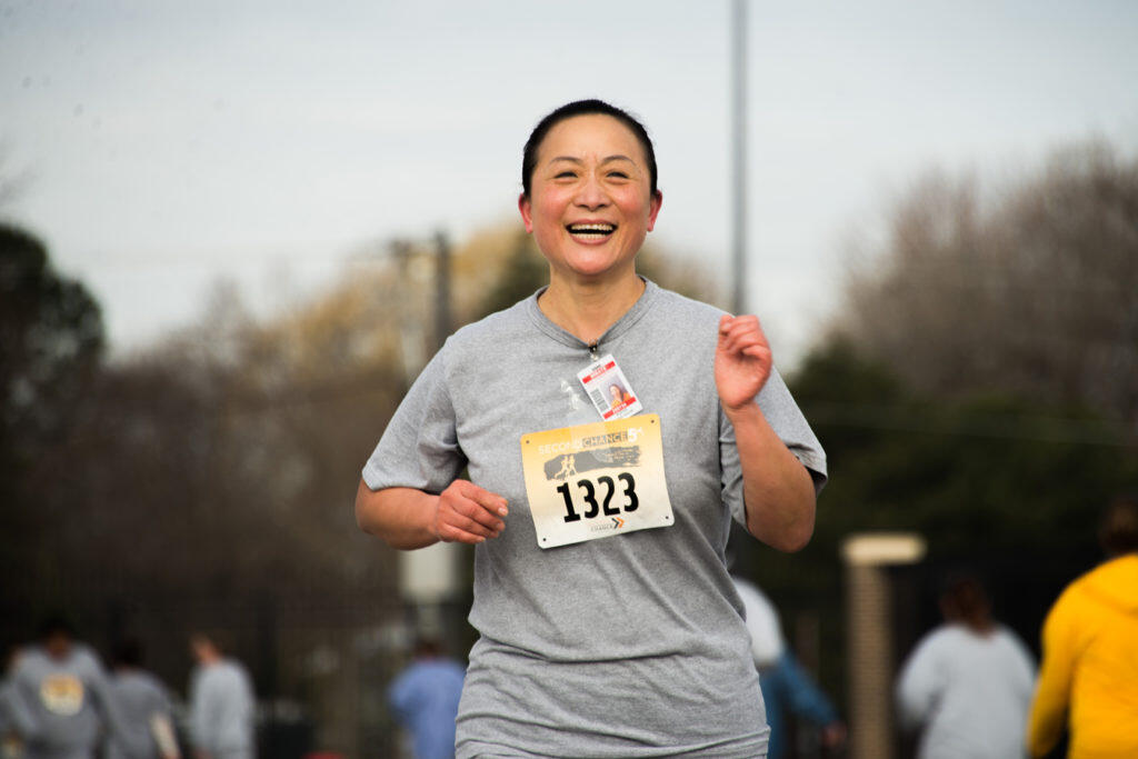A woman smiling as she runs in the race