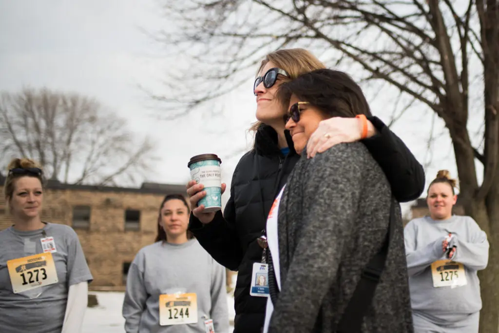 A woman hugs another women as inmates look on