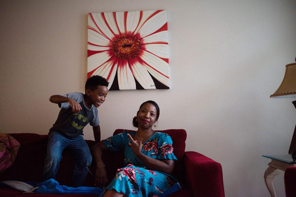 A child plays on a couch as his mother points at him