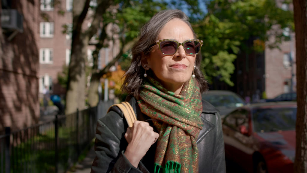 Lenore Skenazy outside wearing sunglasses looking into the distance facing the sunlight