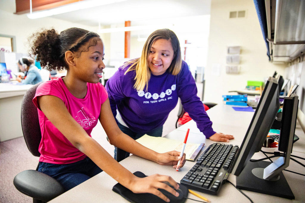 A teacher helping a student with work on a computer