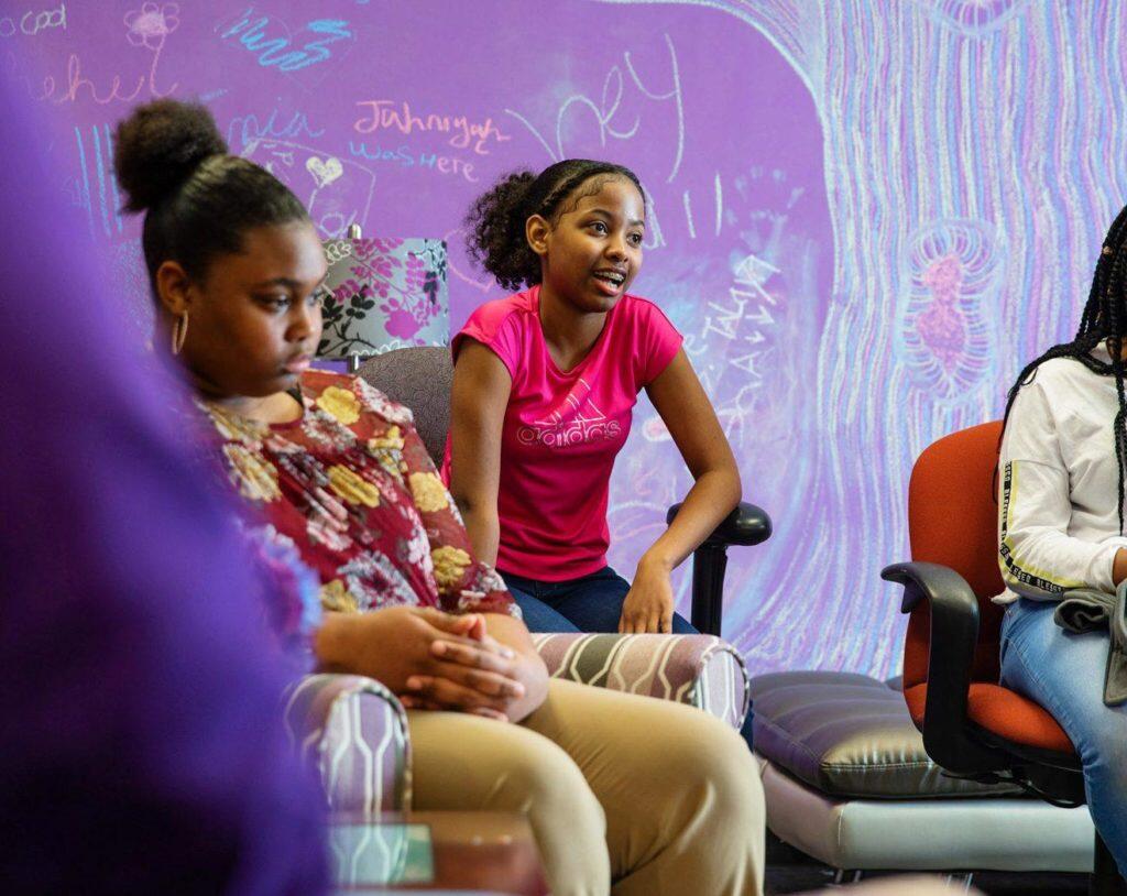 A child speaks in a group of people sitting down
